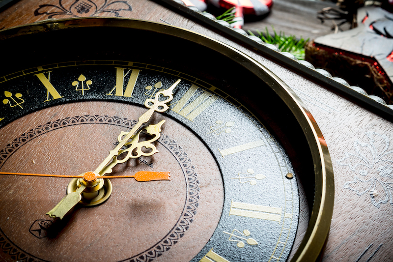 Christmas clock showing one minute to midnight. On rustic background