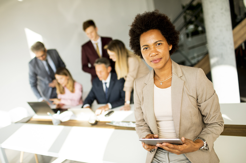 Young African American businesswoman standing and using digital tablet in the modern office