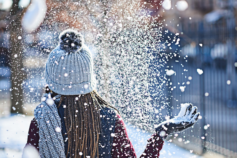 Rearview shot of a young woman throwing snow on a wintery day outdoors.