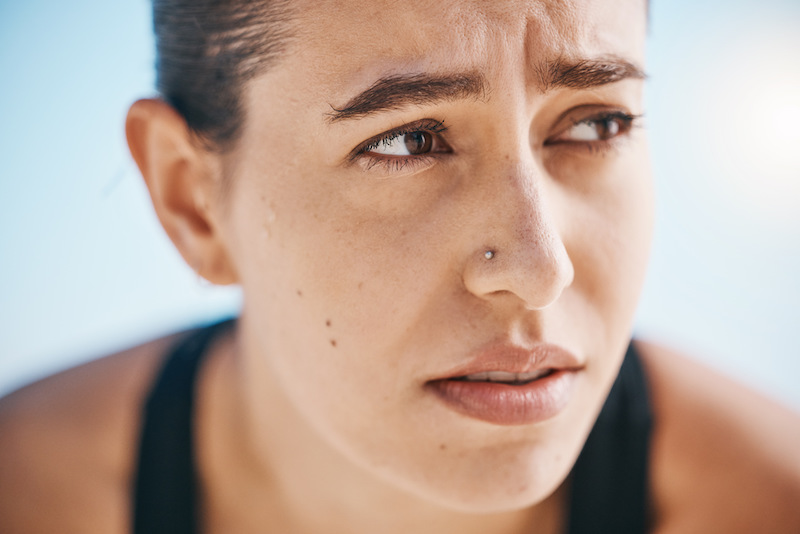 Face, breathing and tired woman on fitness break outdoors after training, running or intense cardio.