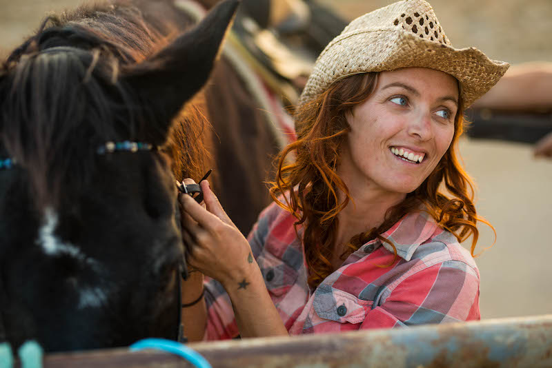 one woman in a farm or in a ranch taking care of her horse smiling and having fun