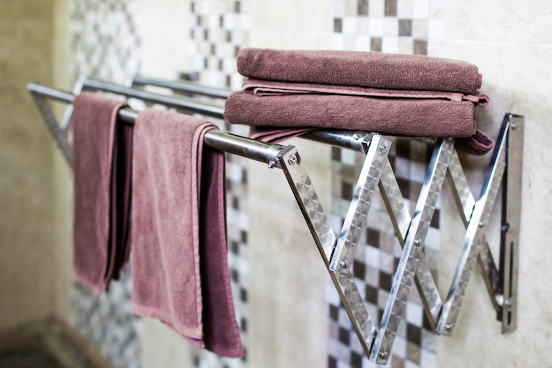 Set of clean hotel towels in bathroom on metal Sliding drier.