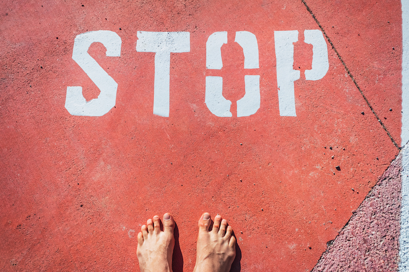 A man in bare feet stops at a stop mark painted on the ground.