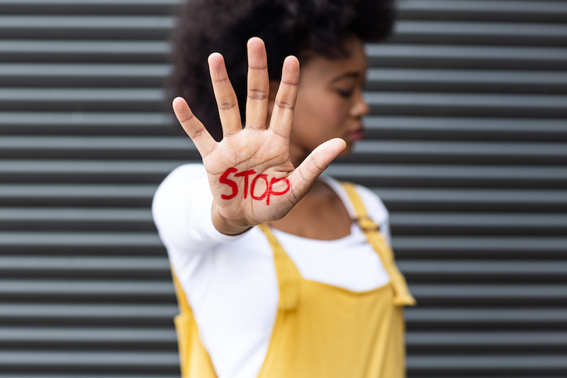 Portrait of mixed race woman making stop gesture with hand covered in writing. equal rights and justice protestors on demonstration march.