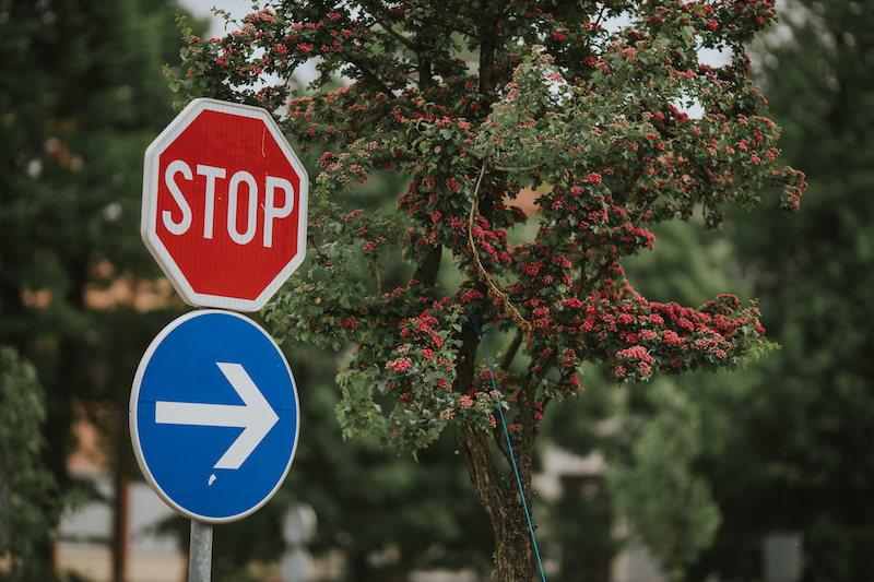 Two regulatory road signs with trees in the background