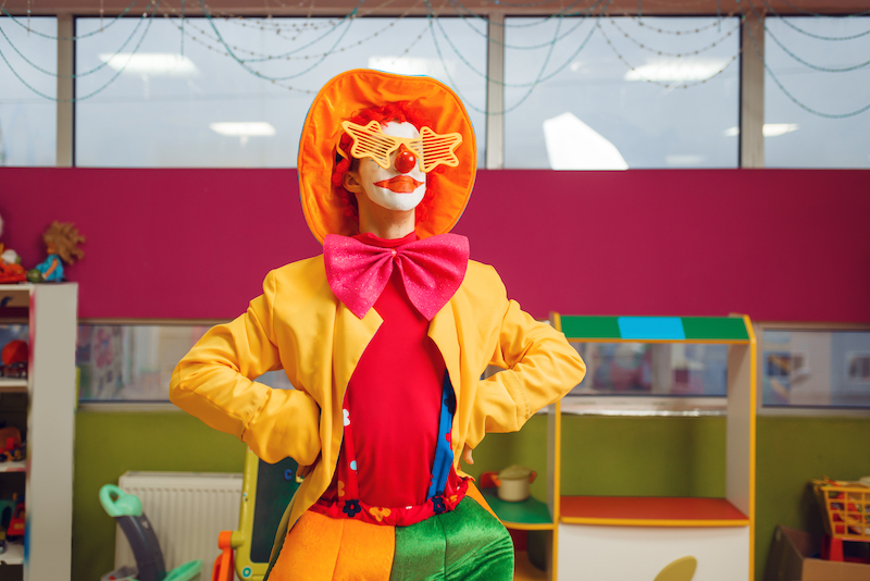 Funny clown in star glasses poses in children's area