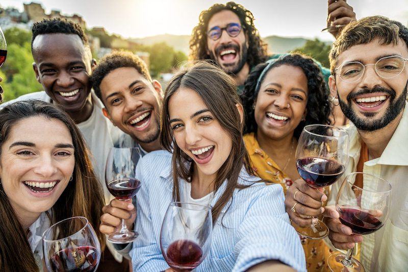 Multiracial friends drinking red wine outside at farm house vineyard countryside - Group of young people taking selfie picture outdoor - Life style concept with guys and girls enjoying summer vacation