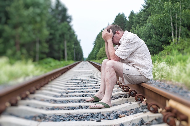 sad man sitting on train tracks