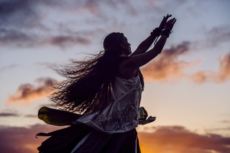 Silhouetted woman hula dancing wearing traditional costume at dusk, Maui, Hawaii, USA