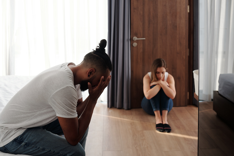 Unhappy offended husband and wife sitting in bedroom apart from each other after big quarrel or fight, divorce and relationship problems concept