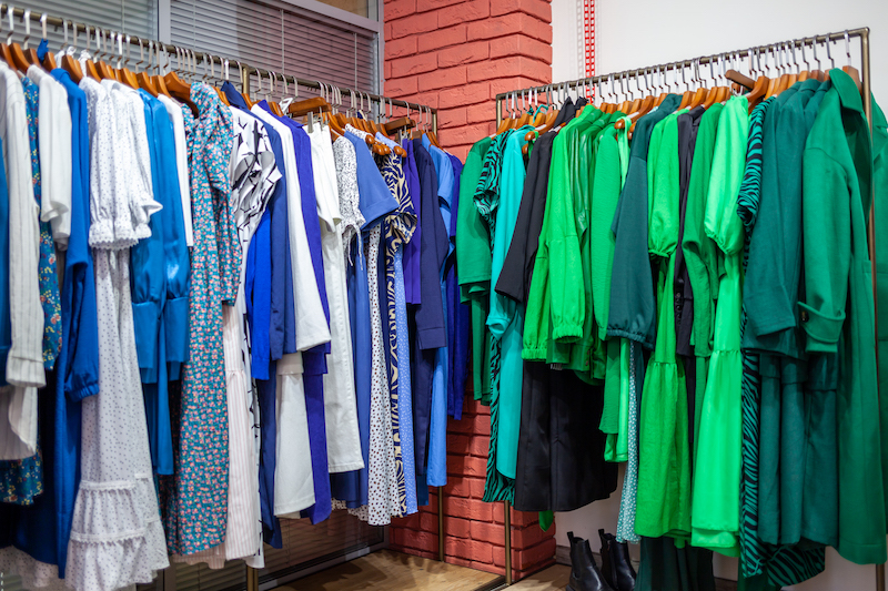 Colorful women's dresses on hangers in a retail shop.