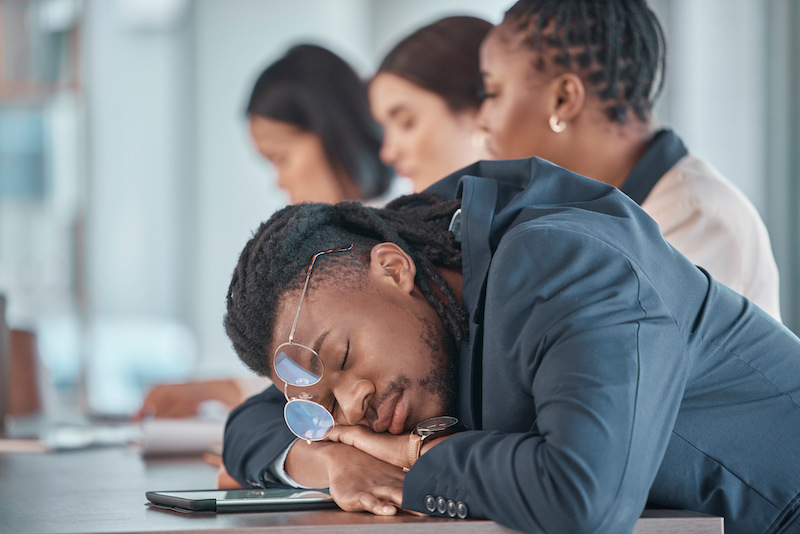 a tired black man sleeping on his desk in class