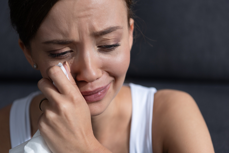 upset young woman crying and wiping tears at home