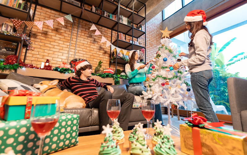 Group of young friends sitting next to a nicely decorated Christmas tree